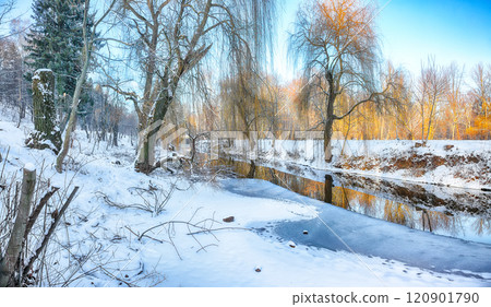 Breathtaking landscape in city park with snowy trees and beautiful reflection in frozen river. 120901790