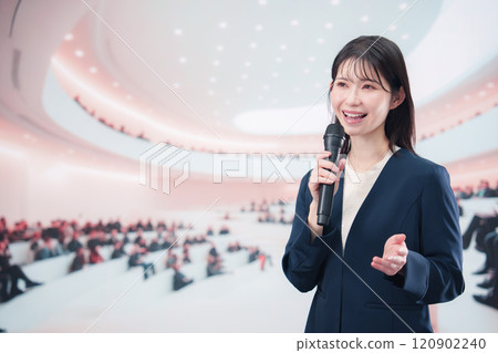 A young woman in a suit giving a presentation in a hall 120902240