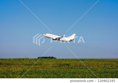 Green field, blue sky and white passenger plane takes off 120902295