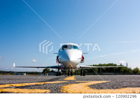 Front view of white private business jet at the parking lot of airport 120902296
