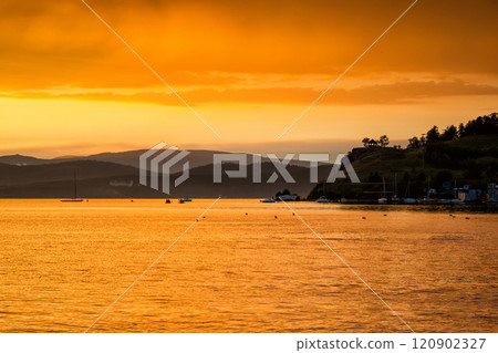 Scenic orange yellow sunset on the lake in a bay with yachts 120902327