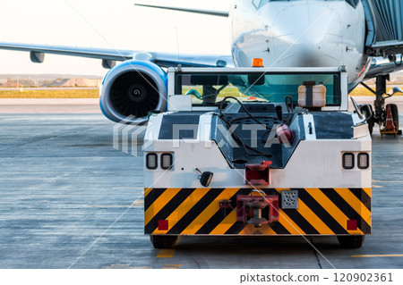 The tow truck drive up at the passenger aircraft parked to a jet bridge The tow truck drive up at the passenger aircraft parked to a jet bridge 120902361