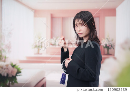A female attendee offering incense at a funeral A female attendee offering incense at a funeral 120902389