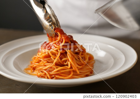 Chef serving pasta with tomato sauce in a restaurant 120902403