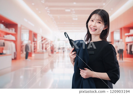 A female sales clerk serving customers at a clothing store 120903194