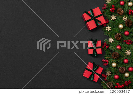 Christmas border with gifts, fir branches and festive decor on black background. New Year background with copy space. Top view, flat lay. Christmas border with gifts, fir branches and festive decor on black background. New Year background with copy space. Top view, flat lay. 120903427
