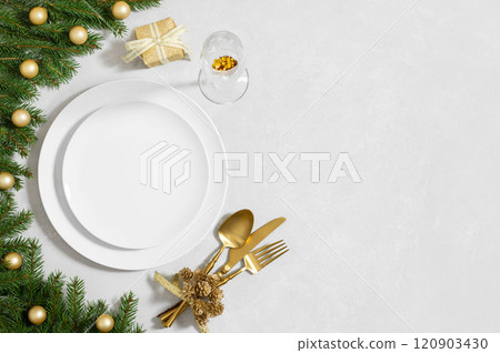 Empty white plate with golden cutlery, festive decor and fir branches on white background. Preparations for Christmas dinner. Copy space. Top view, flat lay. Empty white plate with golden cutlery, festive decor and fir branches on white background. Preparations for Christmas dinner. Copy space. Top view, flat lay. 120903430