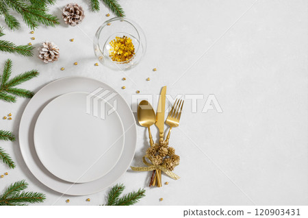 Christmas serving with empty plate, gold cutlery, wine glass and fir branches on white background. Beautiful New Year table setting. Copy space. Top view, flat lay. Christmas serving with empty plate, gold cutlery, wine glass and fir branches on white background. Beautiful New Year table setting. Copy space. Top view, flat lay. 120903431