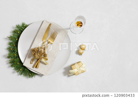 New Year or Christmas table setting with gold decorations and cutlery on white background with copy space. View from above. 120903433