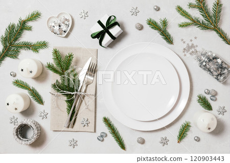 Empty white plate with Christmas silver decorations, candles and fir branches. New Year table setting on white background. View from above. New Year party. 120903443