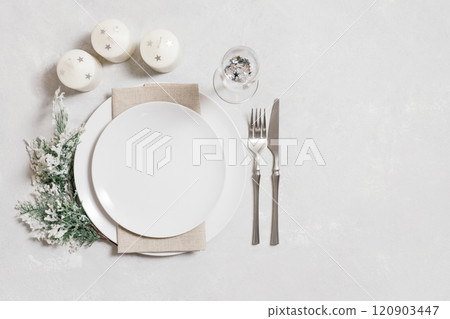 Christmas serving with empty white plate, candles and silverware on white background. Beautiful New Year table setting with copy space. Top view, flat lay. 120903447