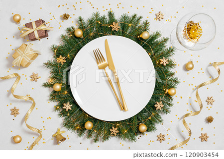Christmas golden table setting with gold decorations and cutlery on white background. Beautiful New Year serving. View from above. Christmas golden table setting with gold decorations and cutlery on white background. Beautiful New Year serving. View from above. 120903454