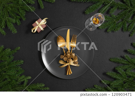 Christmas table setting with black dishes and gold cutlery on black background. New Year serving for a festive dinner. View from above. 120903471