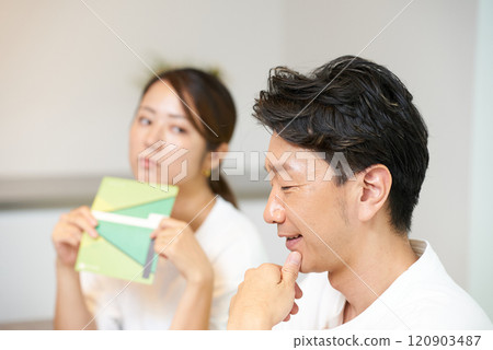 A man is looked at suspiciously by a woman holding a bankbook A man is looked at suspiciously by a woman holding a bankbook 120903487