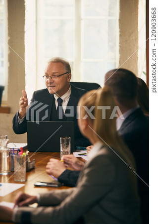 Diverse team of professionals participates in strategic discussion led by senior leader in formal office setting. Lively brainstorming session. Diverse team of professionals participates in strategic discussion led by senior leader in formal office setting. Lively brainstorming session. 120903668