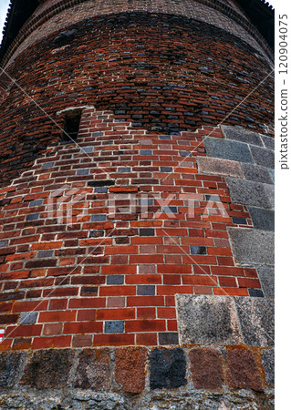 Close-up of a medieval brick tower wall with weathered masonry. Highlights historical architecture, restoration, and craftsmanship in medieval structures. 120904075
