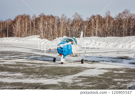 Small white sports airplane on the apron of a snowy airfield in cold winter Small white sports airplane on the apron of a snowy airfield in cold winter 120905587