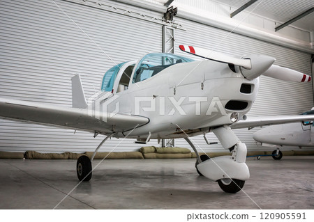 Small sports airplane with opened cockpit canopy in the hangar 120905591