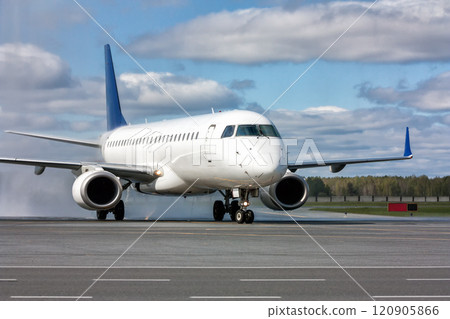 Taxiing a white passenger jet plane after passing through a water arch 120905866