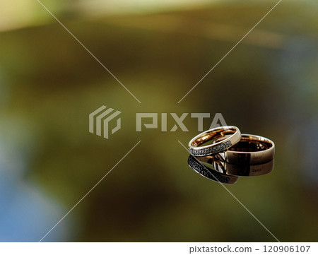 Two gold wedding rings are on a blue surface 120906107