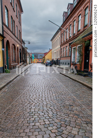 An empty narrow cobblestone street with old colorful buildings with brick walls, Lund, Sweden 120906243