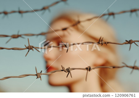 Barbed wire with a blurred woman in the background Barbed wire with a blurred woman in the background 120906761