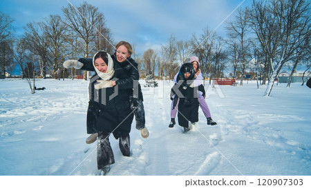 Four happy schoolgirls having piggyback rides in a snowy park, rejoicing in winter and friendship through fun activities Four happy schoolgirls having piggyback rides in a snowy park, rejoicing in winter and friendship through fun activities 120907303
