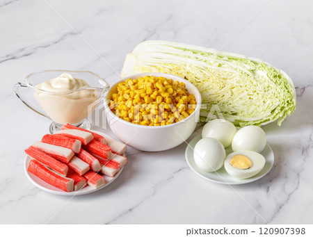 Ingredients for salad: canned sweet corn, surimi sticks, fresh napa cabbage, boiled eggs and mayo over marble countertop. 120907398