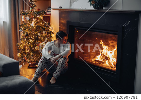a man is sitting by the fireplace and looking at 120907781