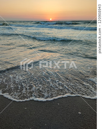 Stormy sea. Big waves with white foam on sea on backdrop of sunset and dawn. Blue sea with orange red sky and sun. Coast seashore seaside sea shore coastline. Natural background nature backdrop storm 120908943