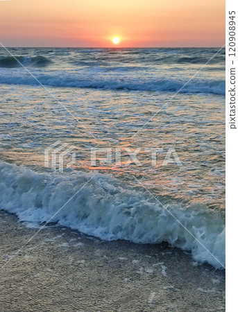 Stormy sea. Big waves with white foam on sea on backdrop of sunset and dawn. Blue sea with orange red sky and sun. Coast seashore seaside sea shore coastline. Natural background nature backdrop storm 120908945
