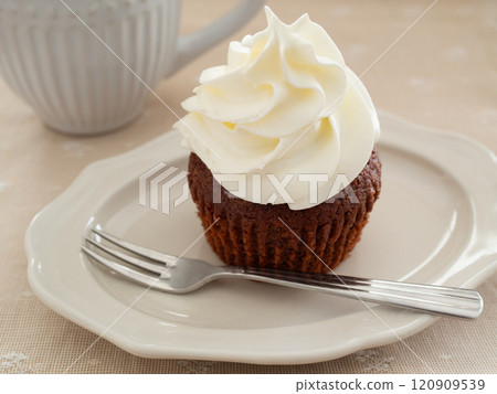 Chocolate muffin topped with whipped cream 120909539