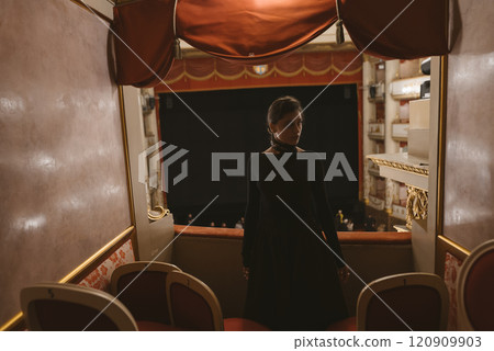 A mysterious figure is seated in a theatre box under the intriguing ambiance of the night 120909903