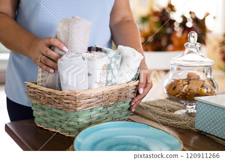 Smiling housewife female kitchen textile towels roll in whicked basket cabinet storage organizing Smiling housewife female kitchen textile towels roll in whicked basket cabinet storage organizing 120911266
