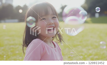 一個女孩天真地微笑著，公園裡有肥皂泡 120911452