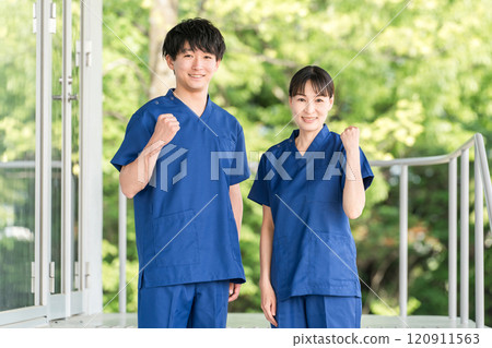 Male and female medical staff (occupational therapists, nurses, doctors, caregivers) wearing scrubs in front of a hospital or facility 120911563