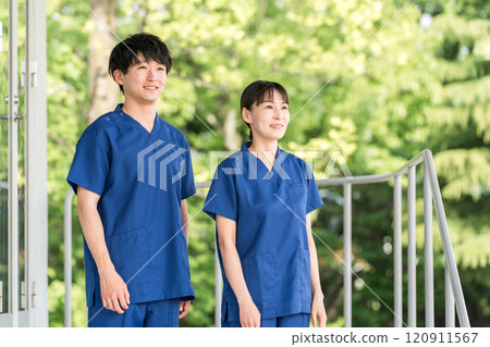 Male and female medical staff (occupational therapists, nurses, doctors, caregivers) wearing scrubs in front of a hospital or facility 120911567