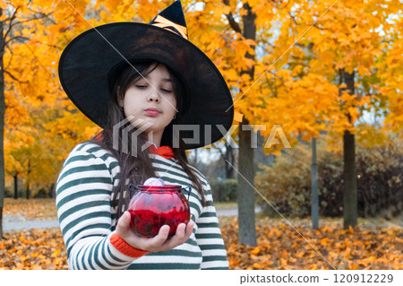 Young witch with magical potion in autumn forest setting 120912229