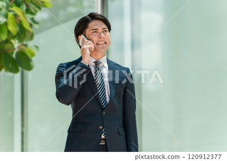 A young businessman commuting to work while discussing business on his smartphone (trouble, mistake, failure, betrayal, apology) 120912377