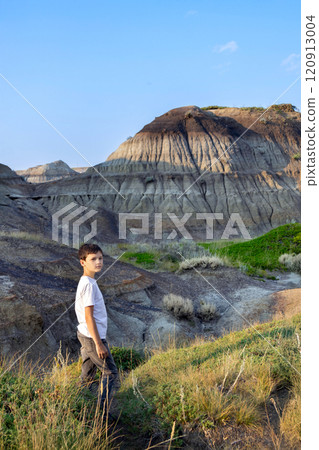 Teenage hiker boy is standing among eroded formations in canyon. 120913004