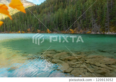 Mountain lake with emerald waters surrounded with forests in fall. Mountain lake with emerald waters surrounded with forests in fall. 120913052
