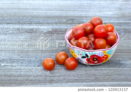 Red cherry tomatoes in a bowl with floral pattern. 120913137
