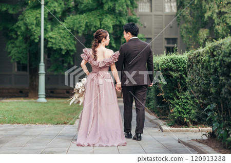 A couple in a colored dress and a suit walking through the garden of a wedding venue (wedding, wedding, bridal) 120913288