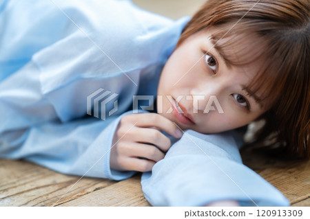 一個留著短鮑伯的年輕女子躺在地板上 120913309