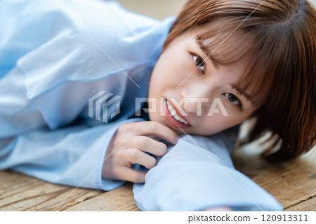 一個留著短鮑伯的年輕女子躺在地板上 120913311