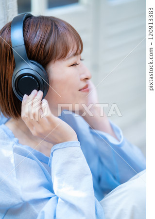 A young woman with a short bob listening to music with headphones 120913383
