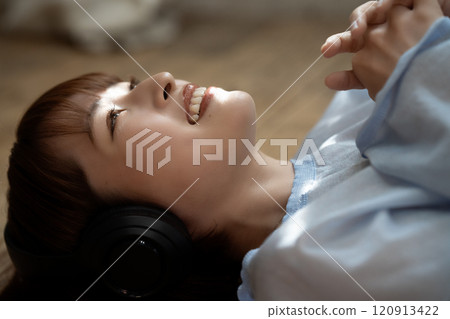 A young woman lying on the floor and listening to music with headphones A young woman lying on the floor and listening to music with headphones 120913422