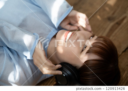 躺在地板上用耳機聽音樂的年輕女子 120913426