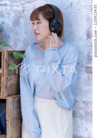 A young woman with a short bob listening to music with headphones A young woman with a short bob listening to music with headphones 120913435