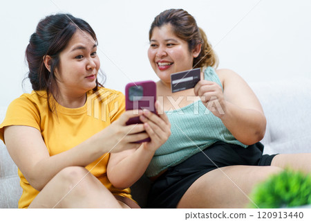 Happy Asian fat women friend excited in online shopping with special discount and using credit card to make a payment. Two Asian fat women staying together and buying goods in e-commerce website. Happy Asian fat women friend excited in online shopping with special discount and using credit card to make a payment. Two Asian fat women staying together and buying goods in e-commerce website. 120913440